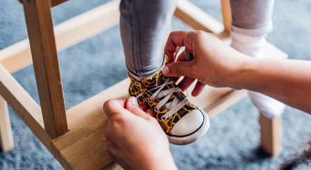 Mother tying child's shoes School Ready